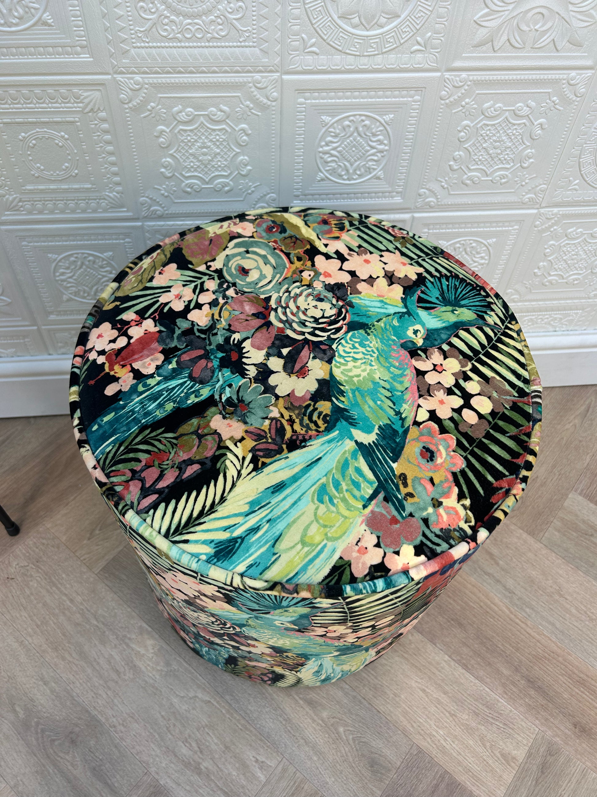 Round stool with a colorful floral and bird pattern.