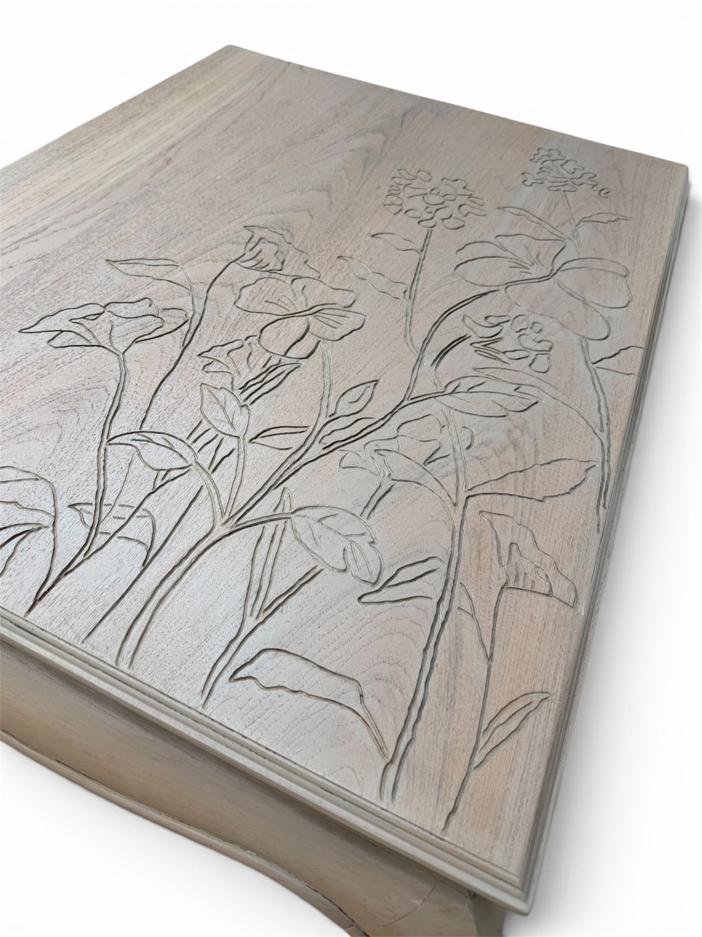 A close-up of a light natural wood top with engraved floral line art. 
