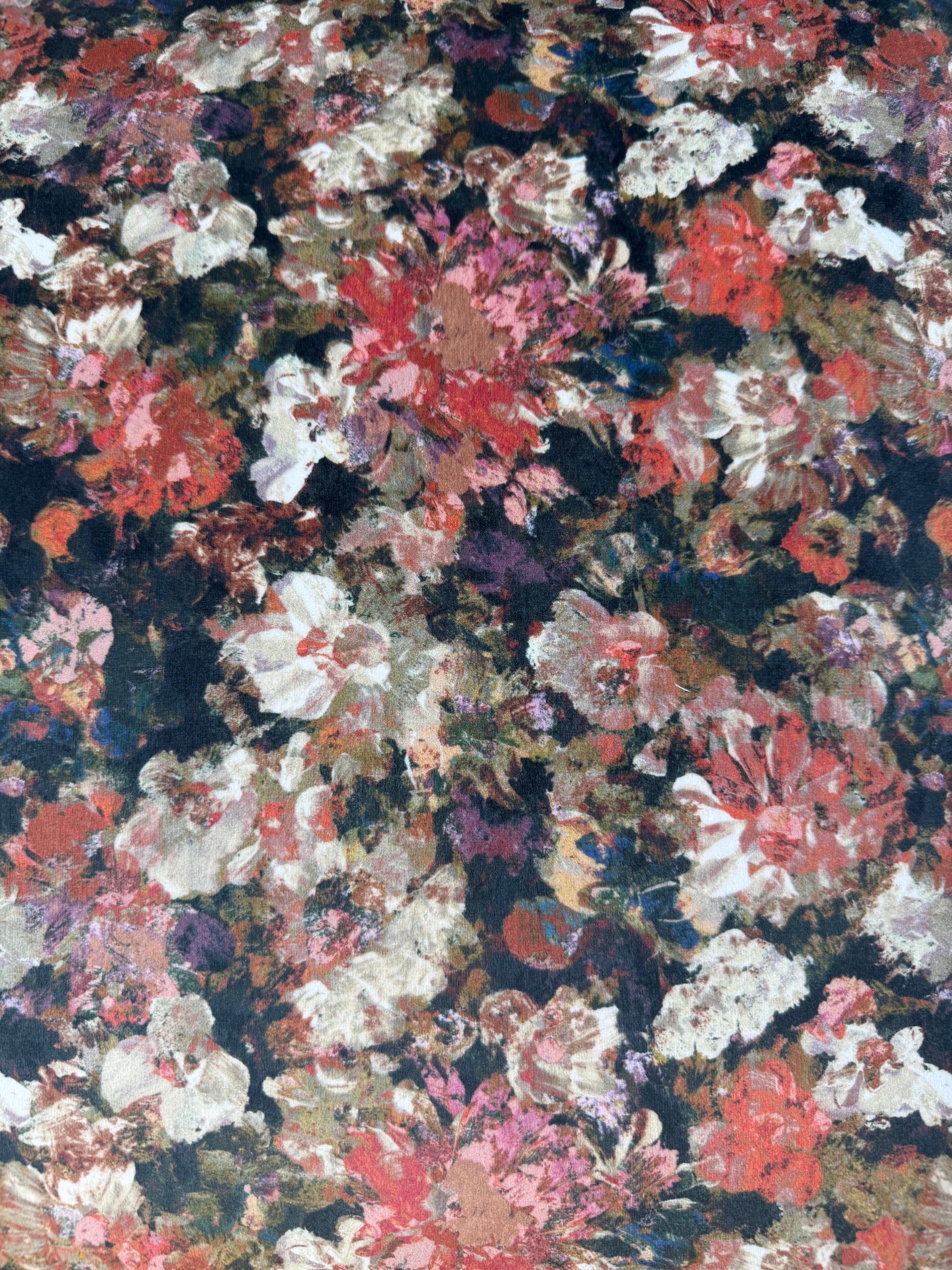 A close-up of a dense floral pattern with painterly brushstrokes in pink, red, white, purple, green, and dark navy/black tones filling the frame.
